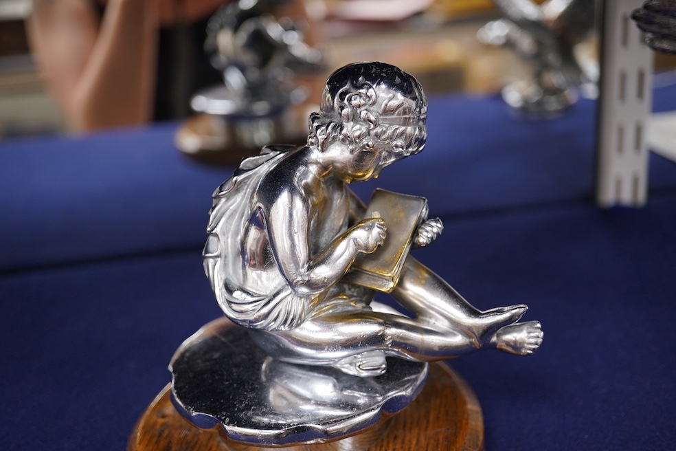 Two chrome car mascots, one in the form of an eagle stamped Finnigans London, wingspan 26cm, and the other of a classical child writing, mounted on a substantial radiator cap and oak base. Condition - fair to good, some
